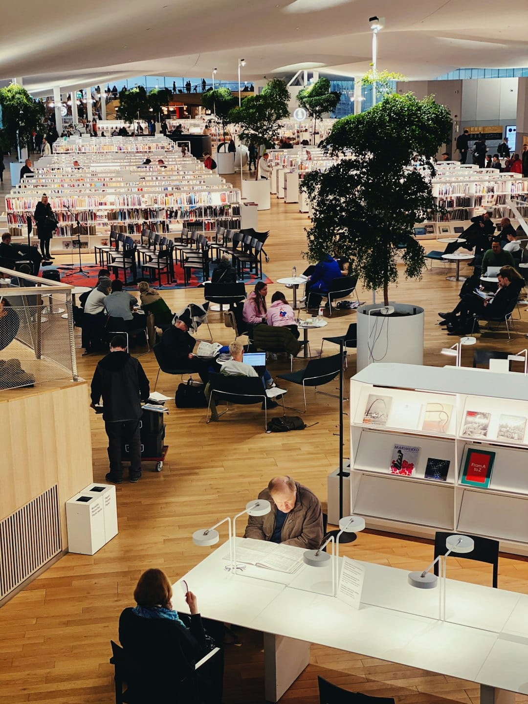Menschen lesen und arbeiten in einer hellen, modernen mehrstöckigen Bibliothek.